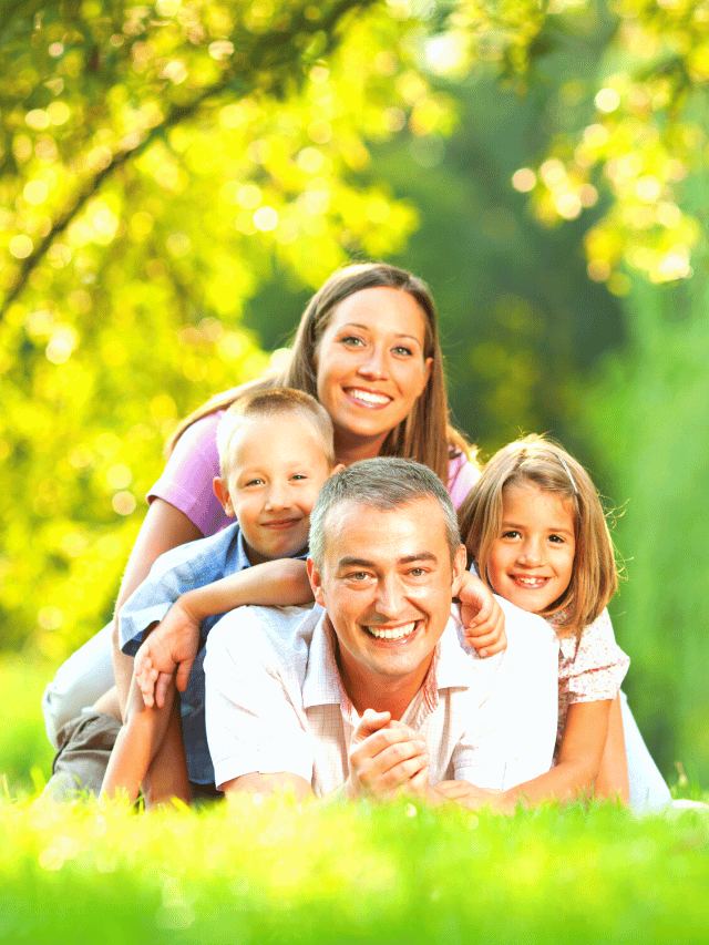 família deitada na grama olhando para a câmera e todos estão sorrindo