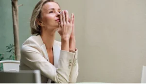 O que é um seguro de vida. Imagem mostra uma Mulher executiva com as duas mãos sobre a boca, indicando que esta pensativa e prestes a tomar uma decisão