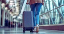 Como viajar mais e melhor em 2026 mostra uma mulher de costa no aeroporto levando uma mala de rodinha