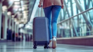 Como viajar mais e melhor em 2026 mostra uma mulher de costa no aeroporto levando uma mala de rodinha